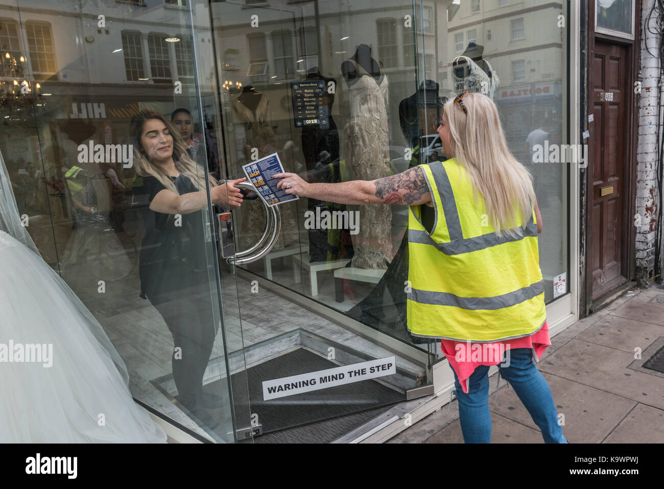 London, UK. 23rd Sep, 2017. London, UK. 23rd September 2017. One of the march stewards hands a leaflet to a woman in a shop as hundreds march in North London from a rally in Tottenham to Finsbury Park against the so called Haringey Development Vehicle, under which Haringey Council is making a huge transfer of council housing to Australian multinational Lendlease. This will result in the imminent demolition of over 1,300 council homes on the Northumberland Park estate, followed by similar loss of social housing across the whole of the borough. At Â£2 billion, his is the largest giveaway o Stock Photo