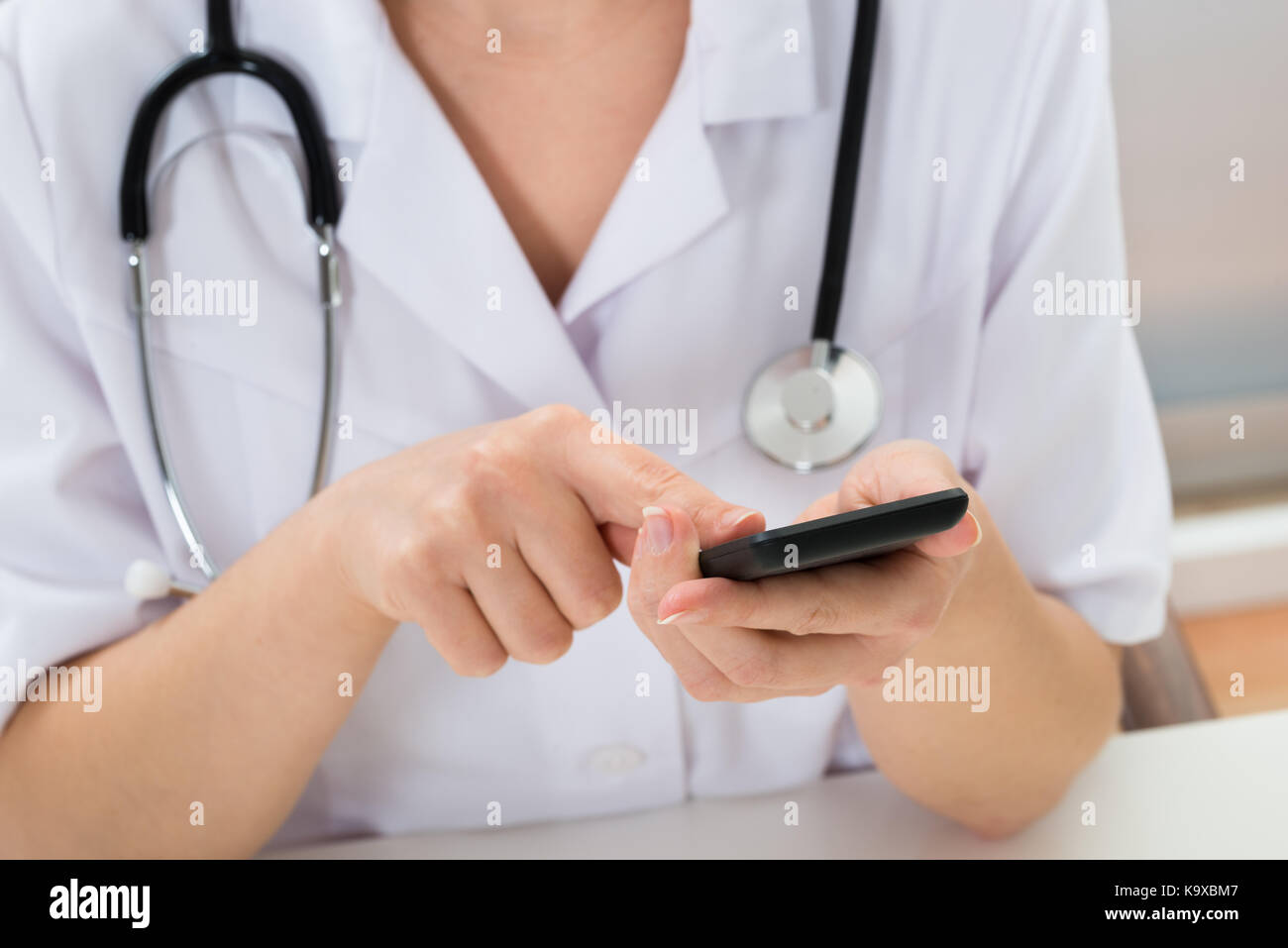 Close-up Of Doctor With Stethoscope Using Mobile Phone Stock Photo