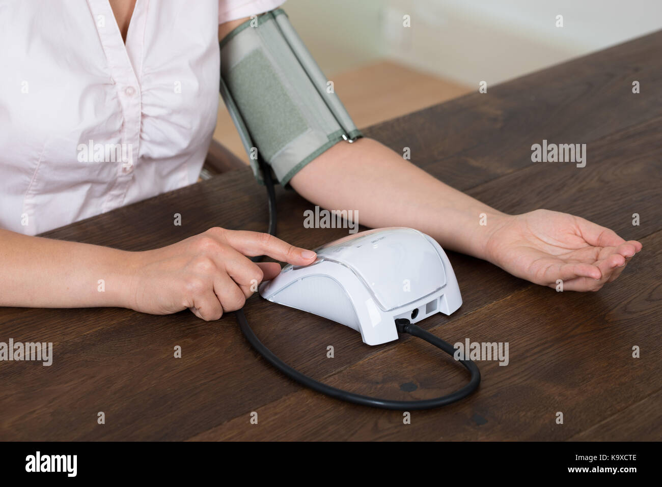 Closeup Of Businesswoman Measuring Blood Pressure At Desk Stock Photo