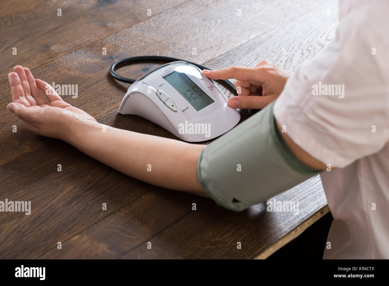 Close-up Of Businesswoman Measuring Blood Pressure At Desk Stock Photo