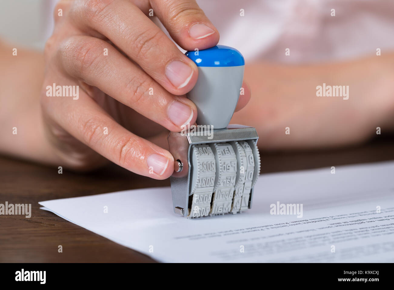 Close-up Of Person Hands Stamping Paper With Date Stamper Stock Photo