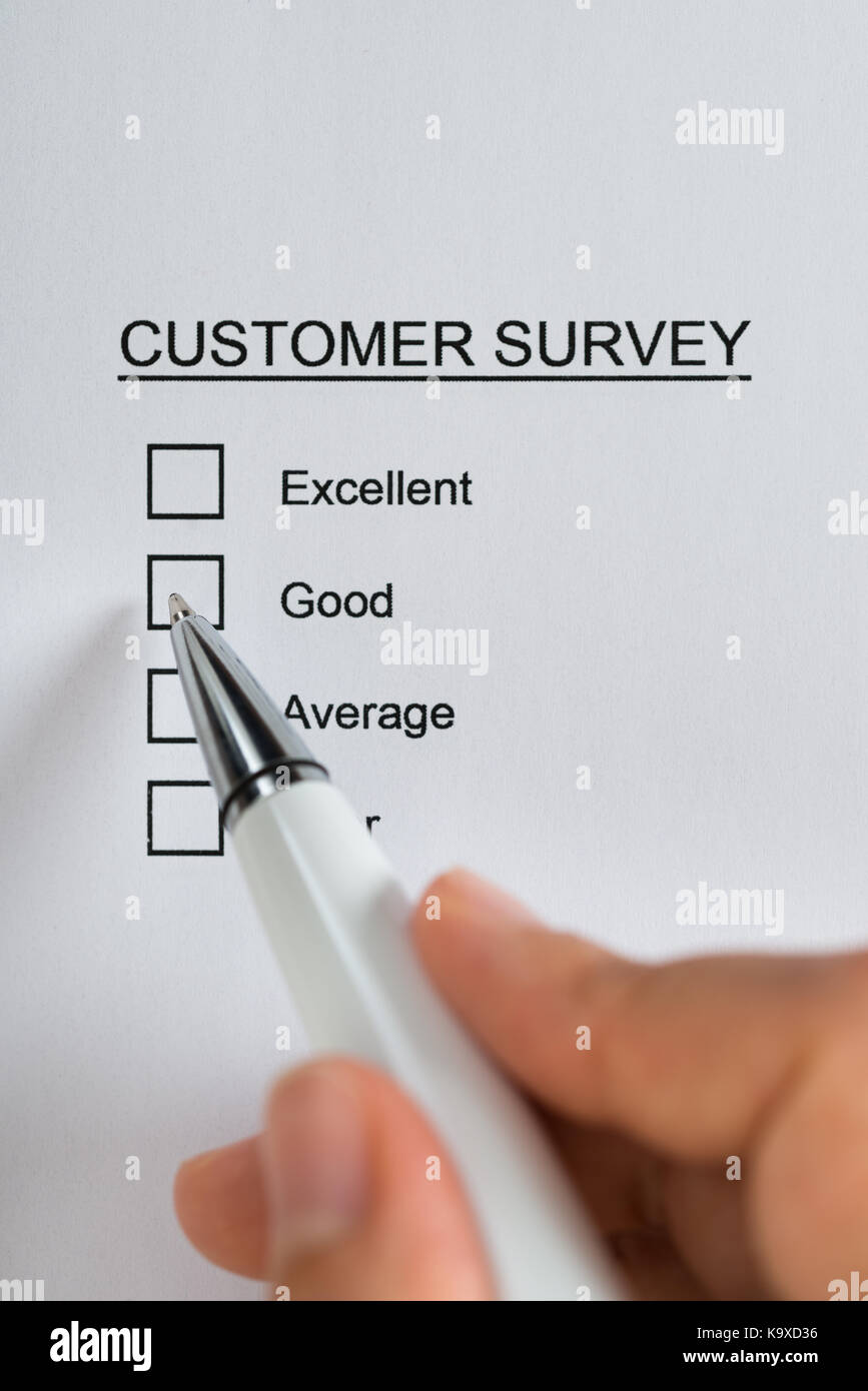 Close-up Of Person Hands Filling Customer Survey Form With Pen Stock Photo