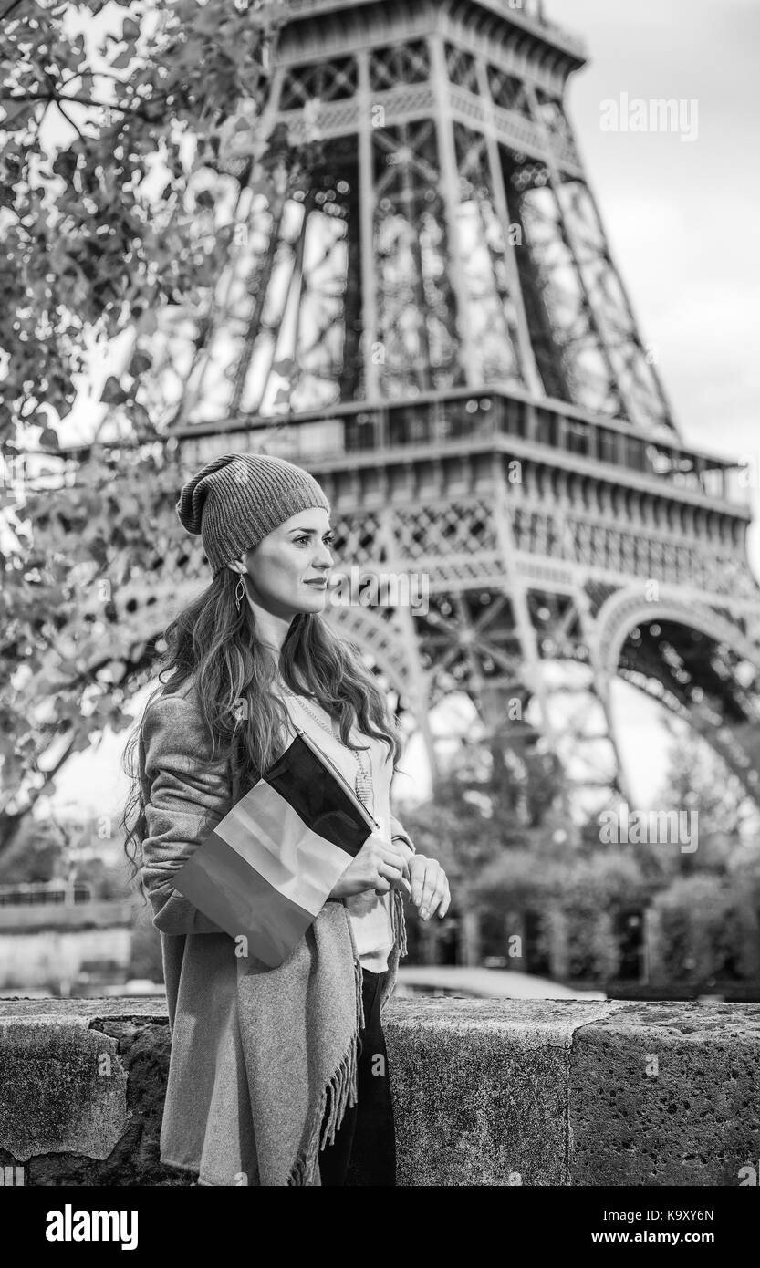 Autumn getaways in Paris. happy young elegant woman on embankment near Eiffel tower in Paris, France with flag Stock Photo