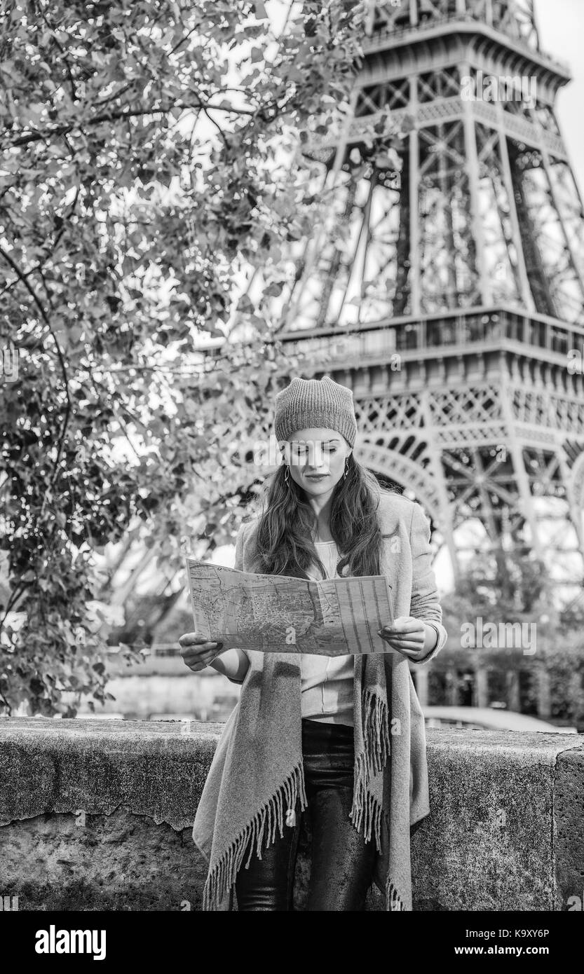 Autumn getaways in Paris. young tourist woman on embankment near Eiffel tower in Paris, France looking at the map Stock Photo