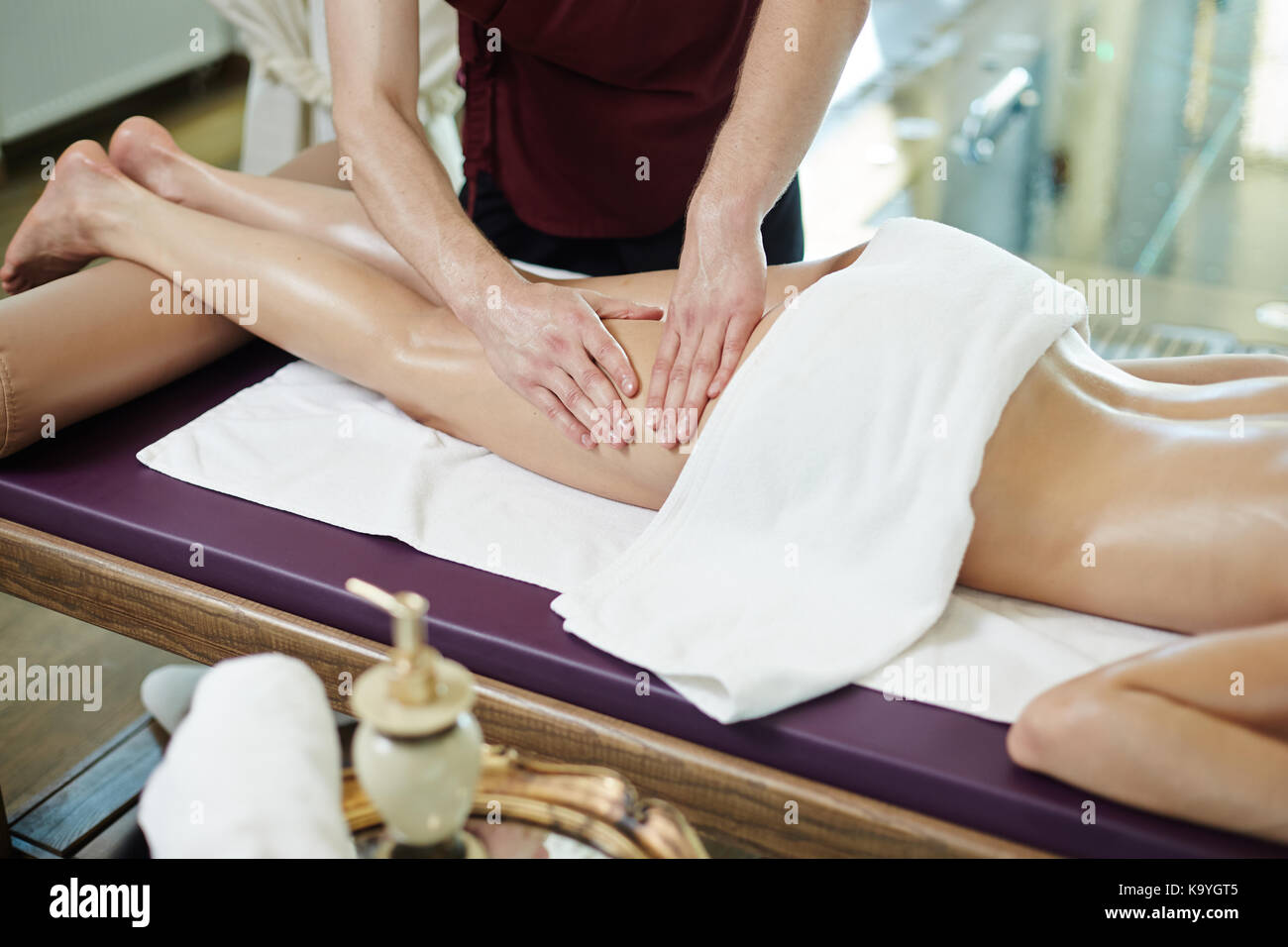 Unrecognizable man massaging legs of young woman lying on massage table in  SPA center Stock Photo - Alamy
