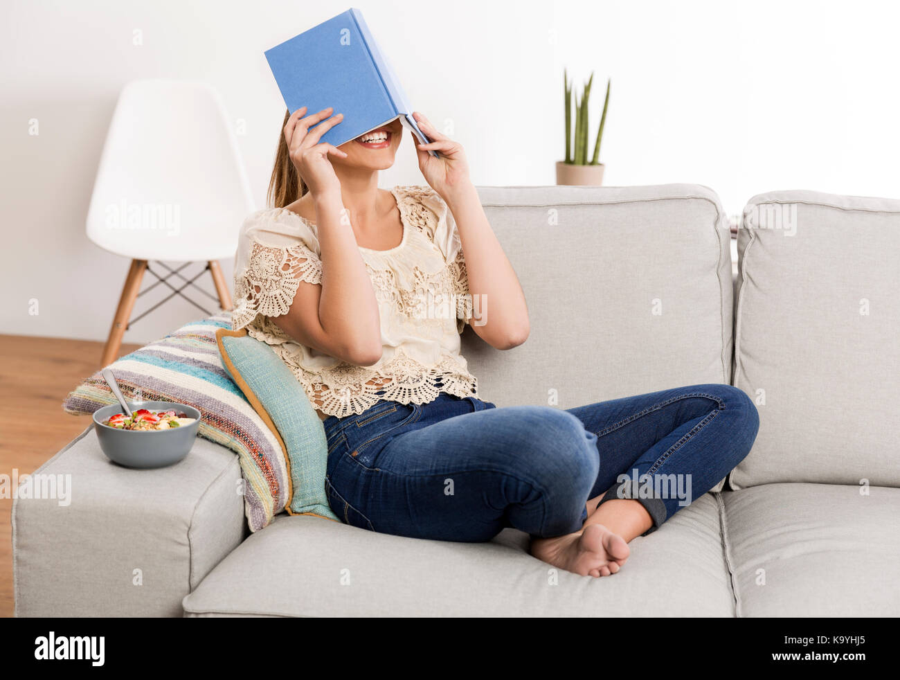 Beautiful woman at home sitting on the couch and reading a book Stock Photo