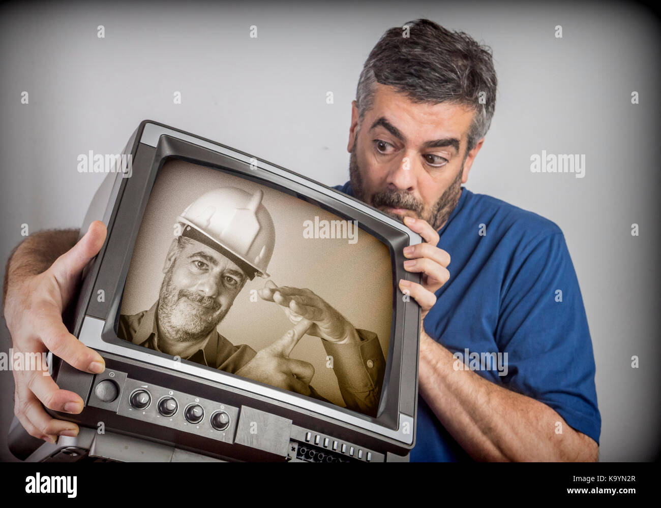 Man subject astonished a TV that is dressed as a stonemason the same Stock Photo