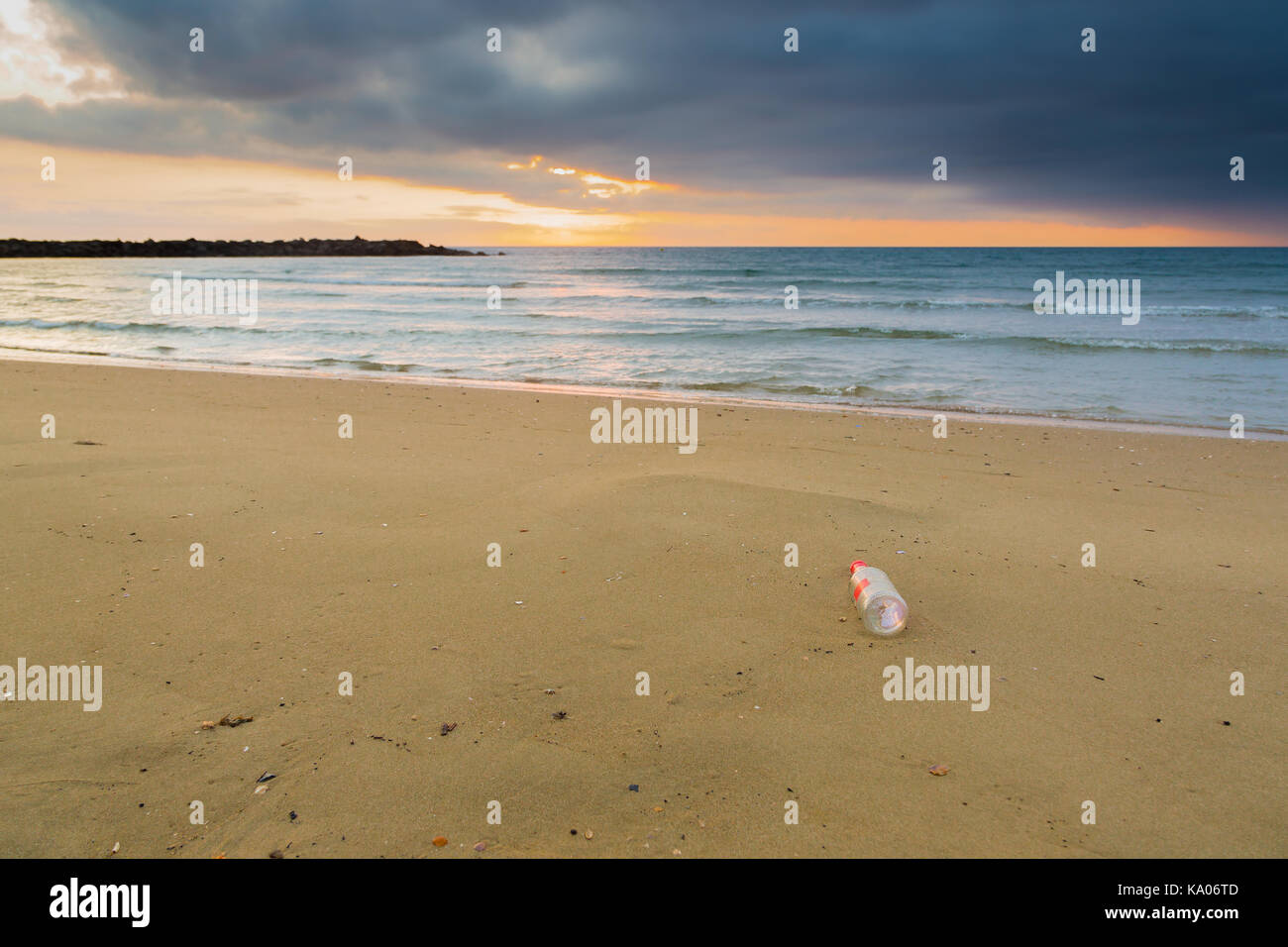 Glass bottle stranded on deserted beach at sunrise Stock Photo
