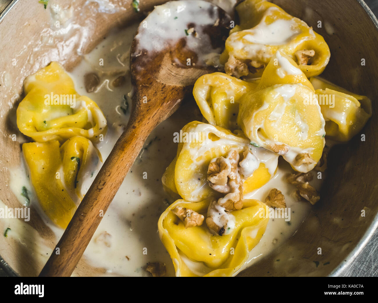 Tortelloni (typical Bologna homemade stuffed pasta) with nuts, cream and sage in their cooking pan Stock Photo