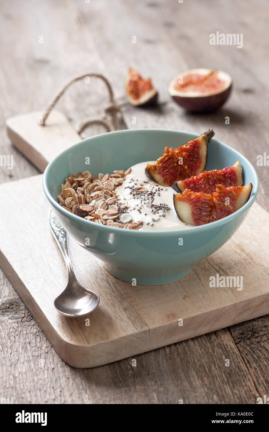 healthy breakfast. muesli, yoghurt, figs, chia seeds in a blue bowl ha old wooden background