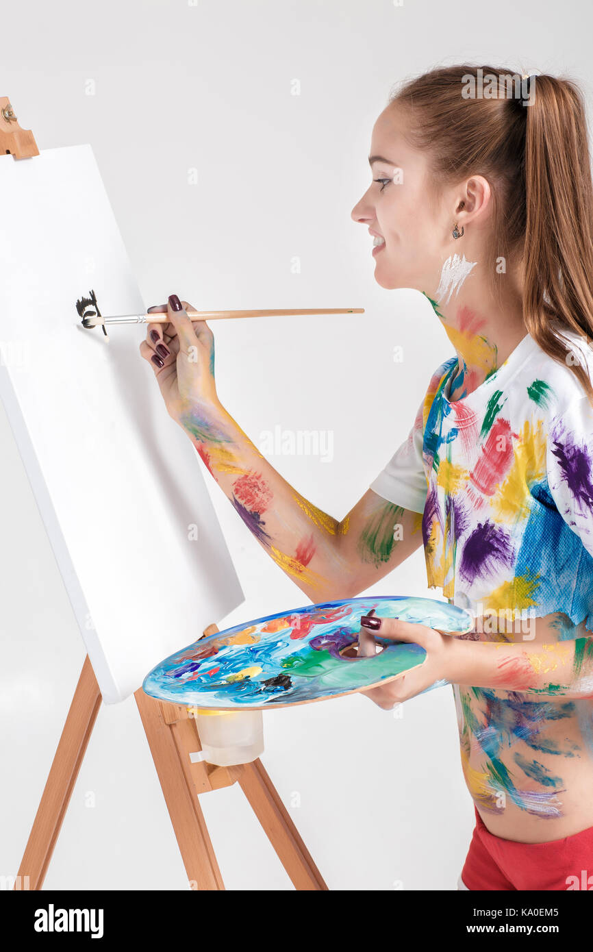 woman painter soiled in colorful paint draws on canvas. Stock Photo