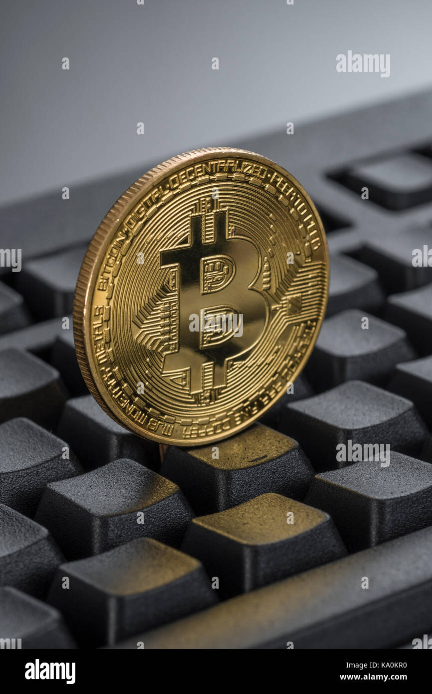 Gold coloured BitCoin / Bitcoin cryptorcurrency token on a black Qwerty keyboard - metaphor for online transactions, Darkweb cybercrime, & e-commerce. Stock Photo