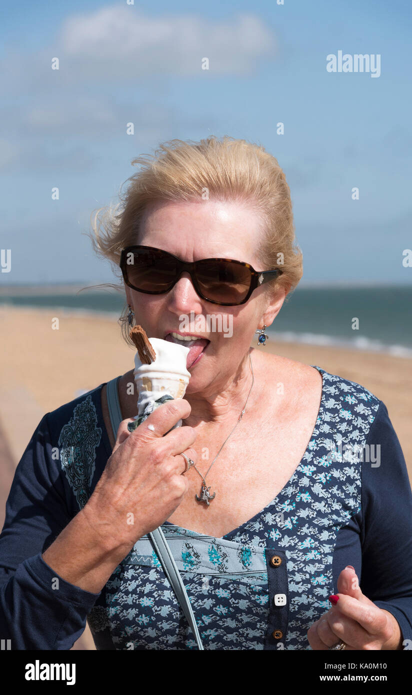 Woman at the seaside eating an ice cream cone Stock Photo