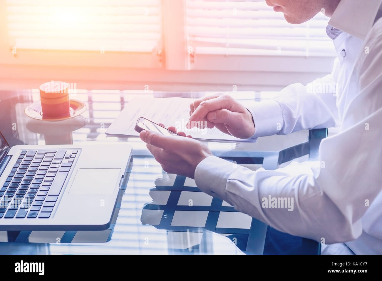 Businessman working in modern office with smartphone and laptop computer to contact his business team Stock Photo