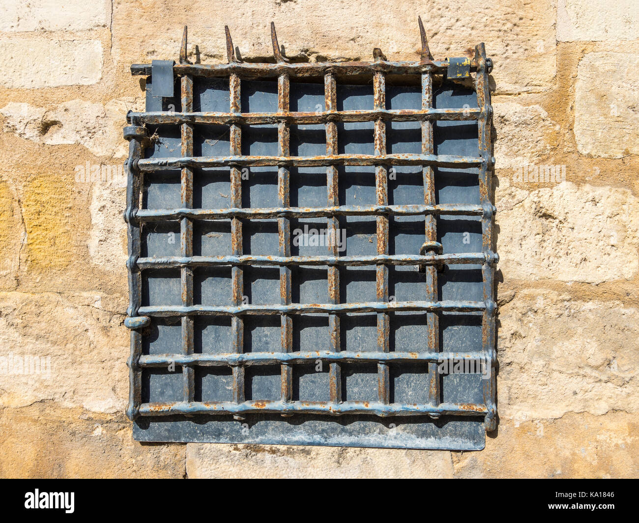 Old metal grating in stone wall - France. Stock Photo