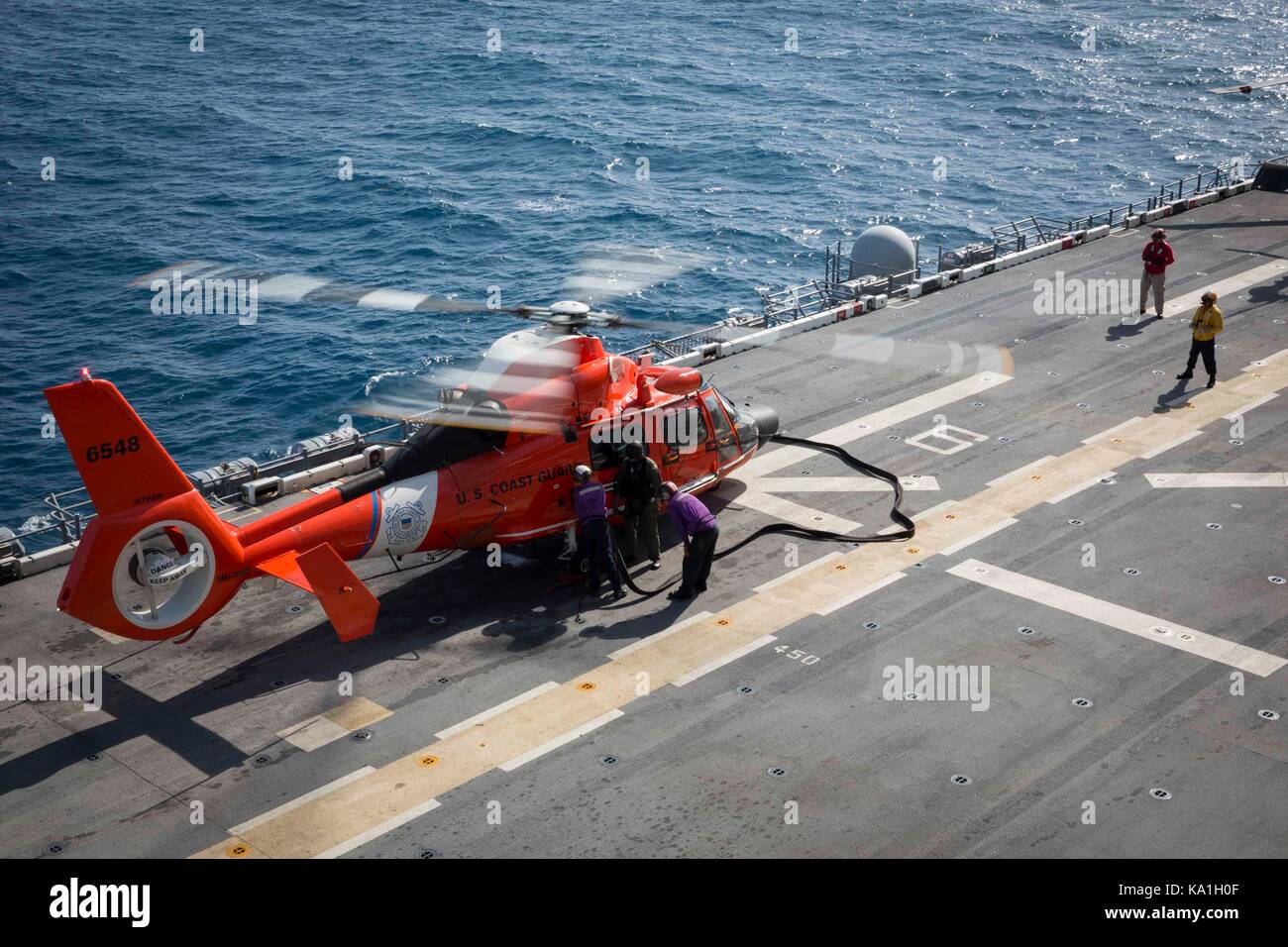 Coast Guard Cutter Forward's embarked HITRON MH-65 Dolphin Helicopter receives fuel from amphibious assault ship USS Kearsarge (LHD 3) on September 24 Stock Photo