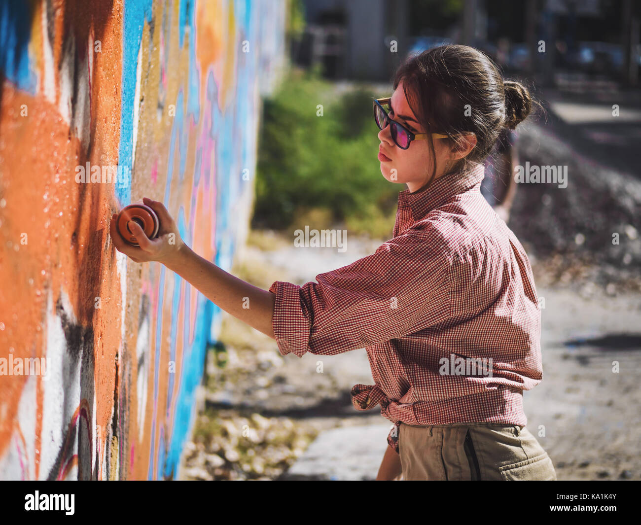 Beautiful Young Girl making a colorful graffiti with aerosol spray on ...