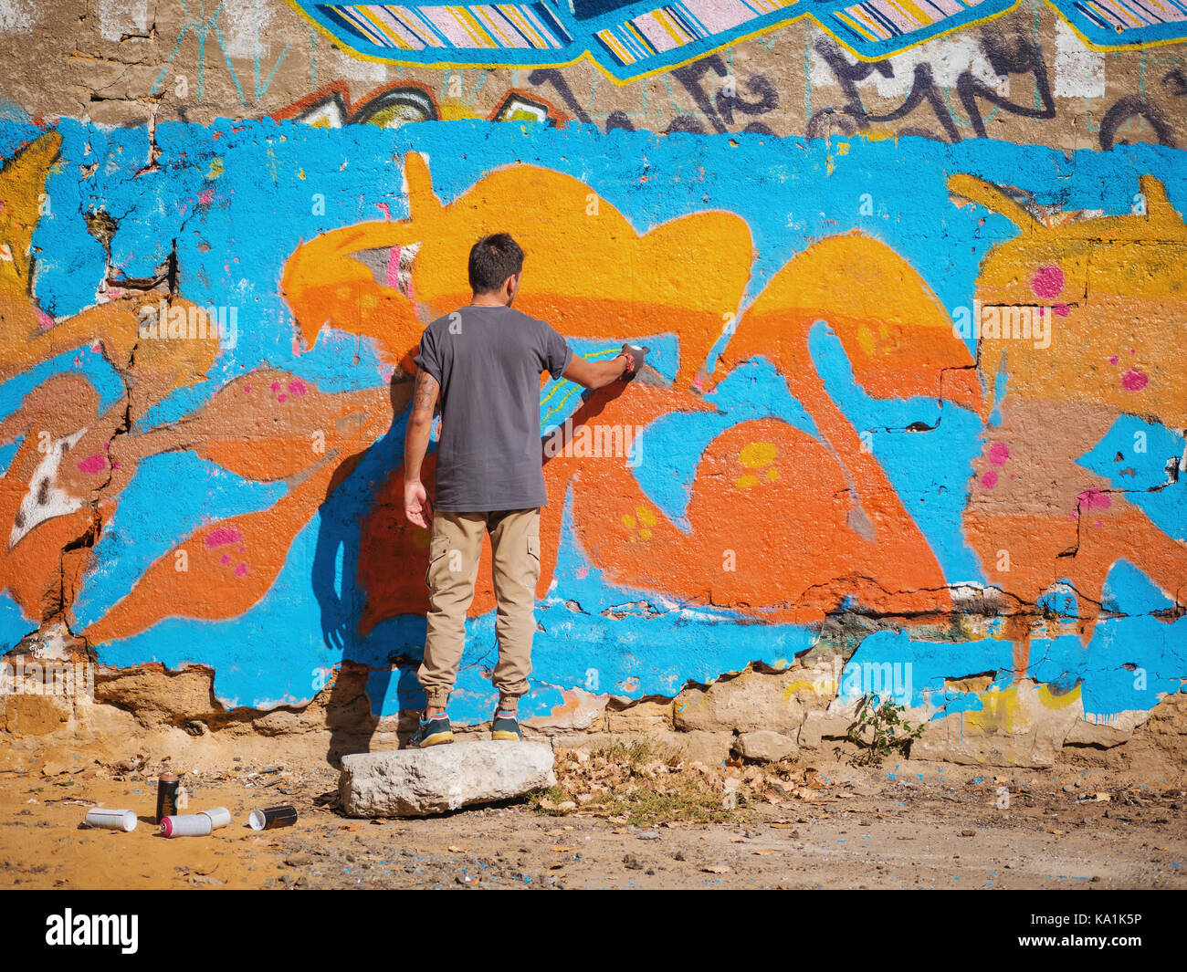 Creative art - teenage boy painting colorful abstract ornament graffiti on  street wall with aerosol spray. Back view, overall plan Stock Photo - Alamy