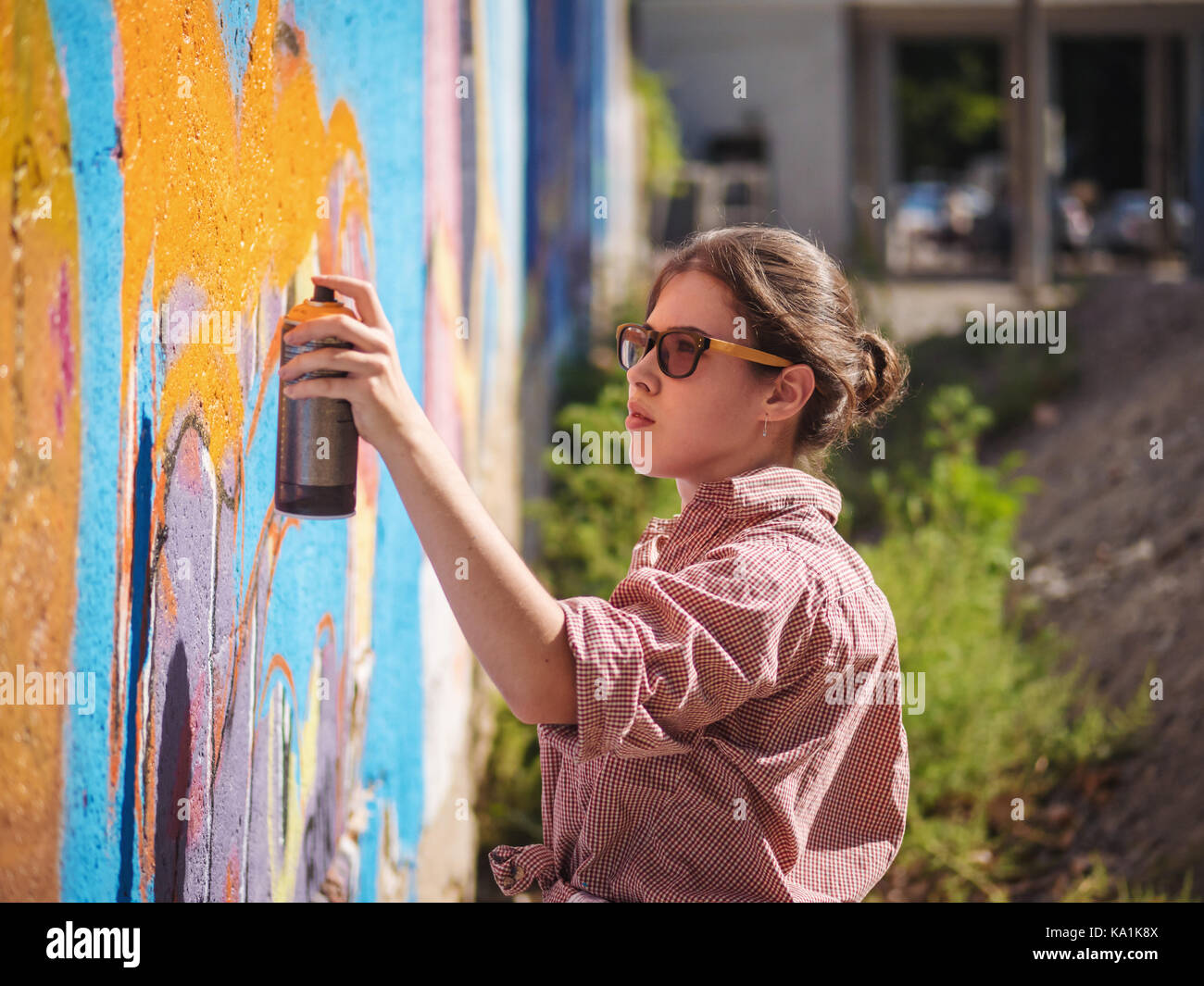 Beautiful Young Girl making a colorful graffiti with aerosol spray on ...