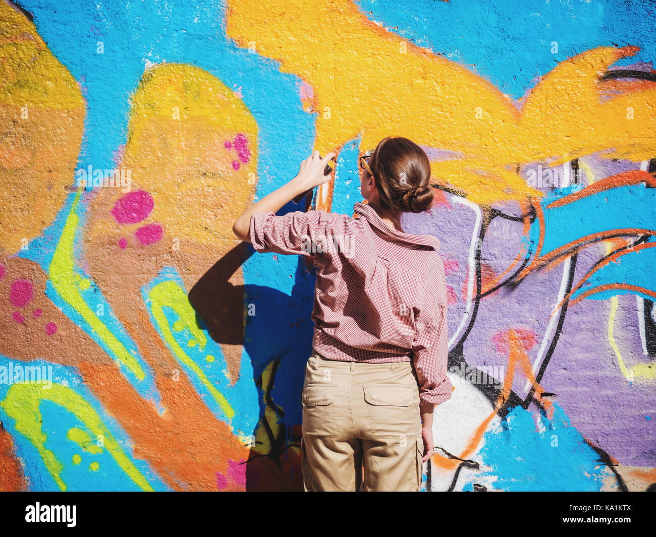 Beautiful Young Girl making a colorful graffiti with aerosol spray on ...