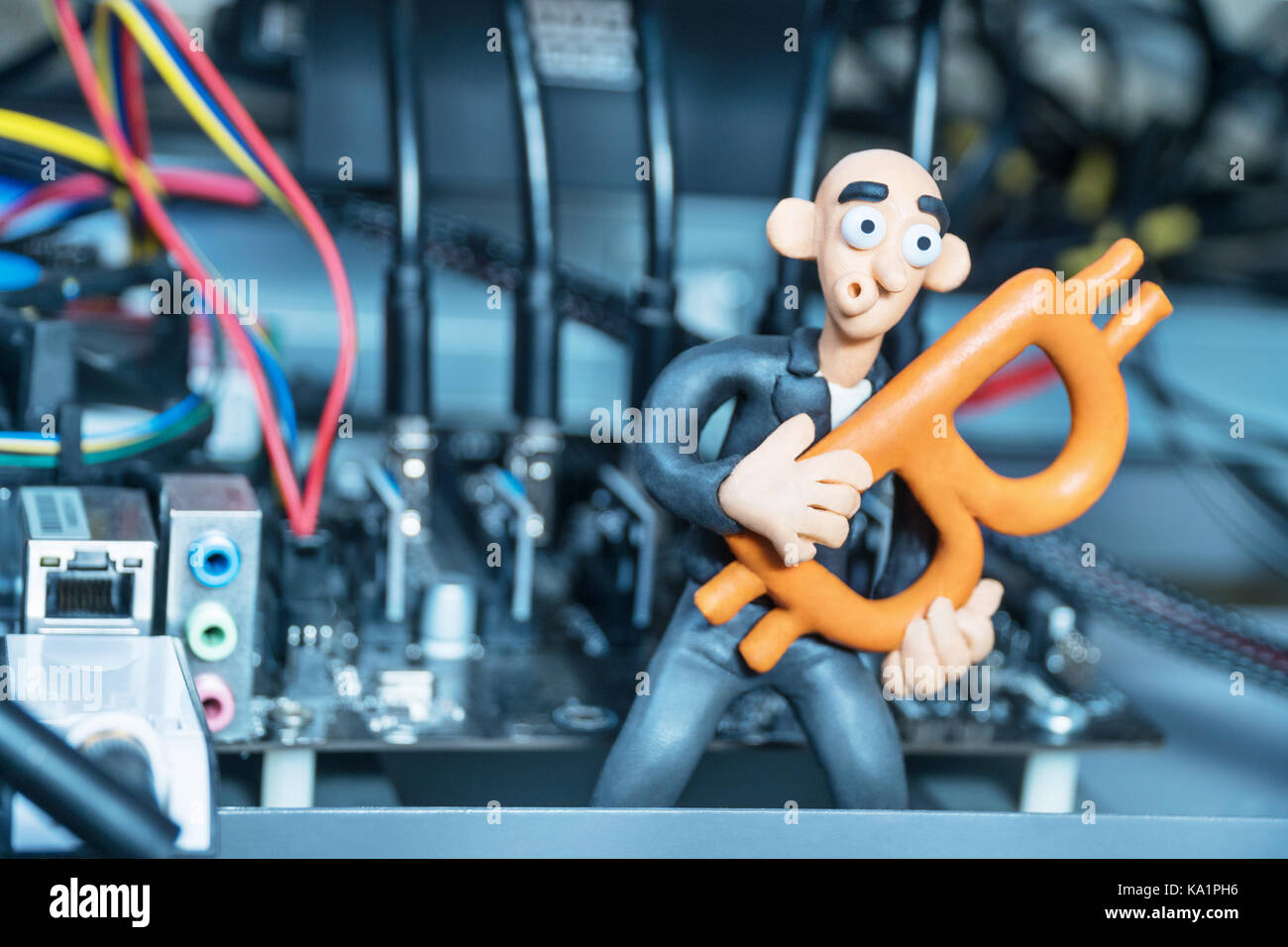 Bald plasticine businessman sits in the computer for mining crypto-currency  with bitcoin in hands Stock Photo - Alamy