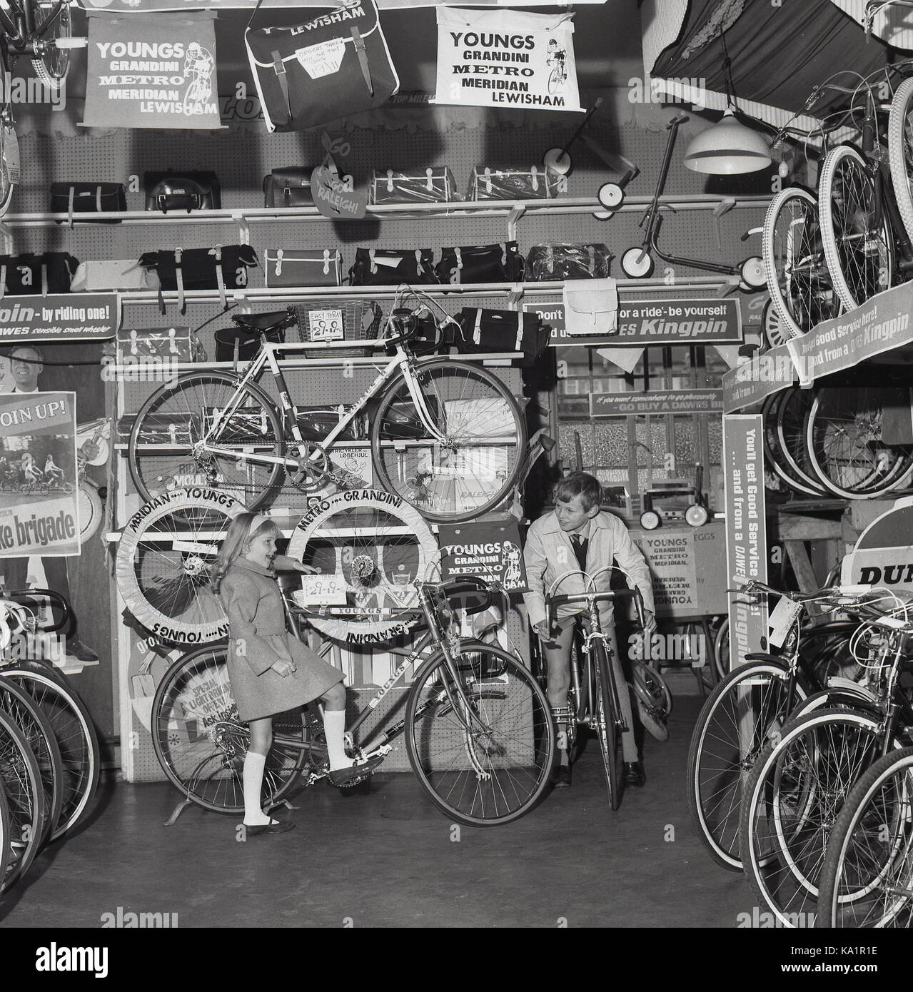 1970s, historical, an exited young boy with sister looking on, sits on one of the racing bikes on display inside the showroom Youngs lightweight cycle shop, Lewisham, South London, England, UK. Stock Photo