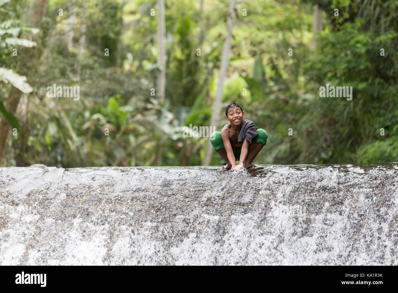 Children from small village under Mount Agung playing in watterfall Stock Photo