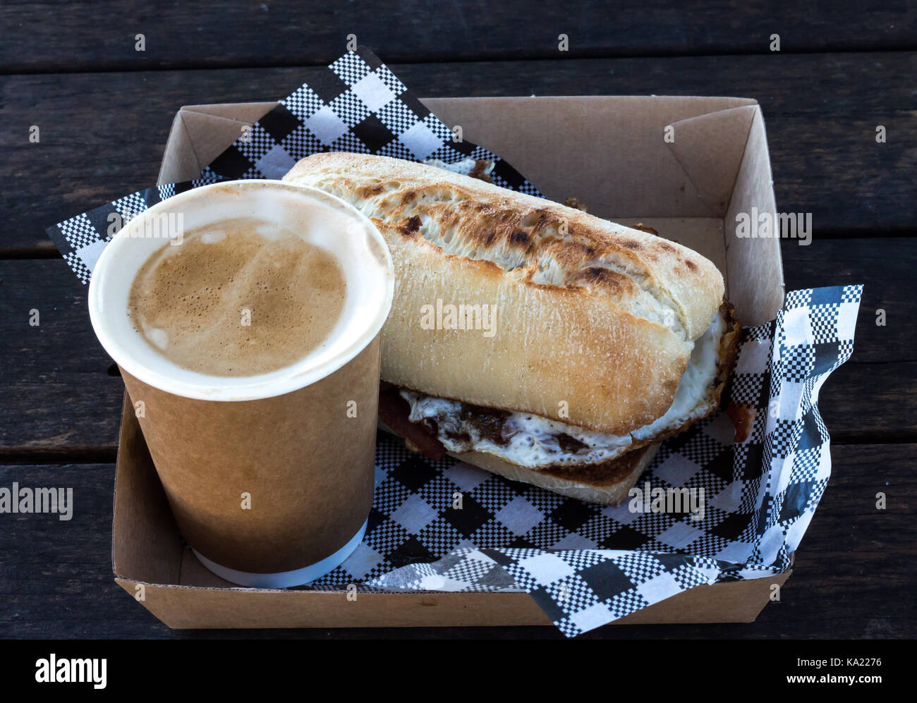 Bacon and egg breakfast ciabatta roll with take away coffee with checkered serviettes in box Stock Photo