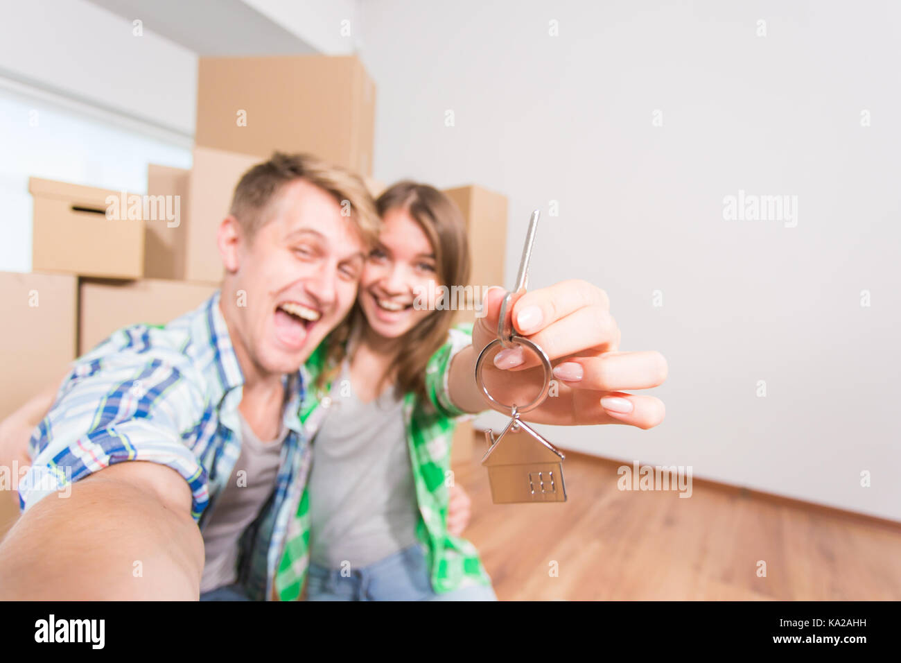 Happy funny couple embracing and showing house key in their new home ...