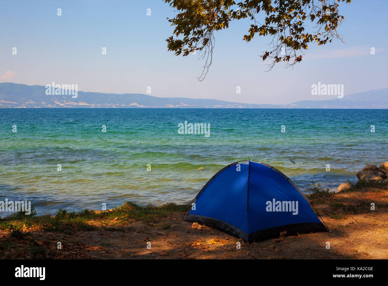 Beach of Stavros town in Greece, one blue tent under the trees with beautiful view on seaside. Stock Photo