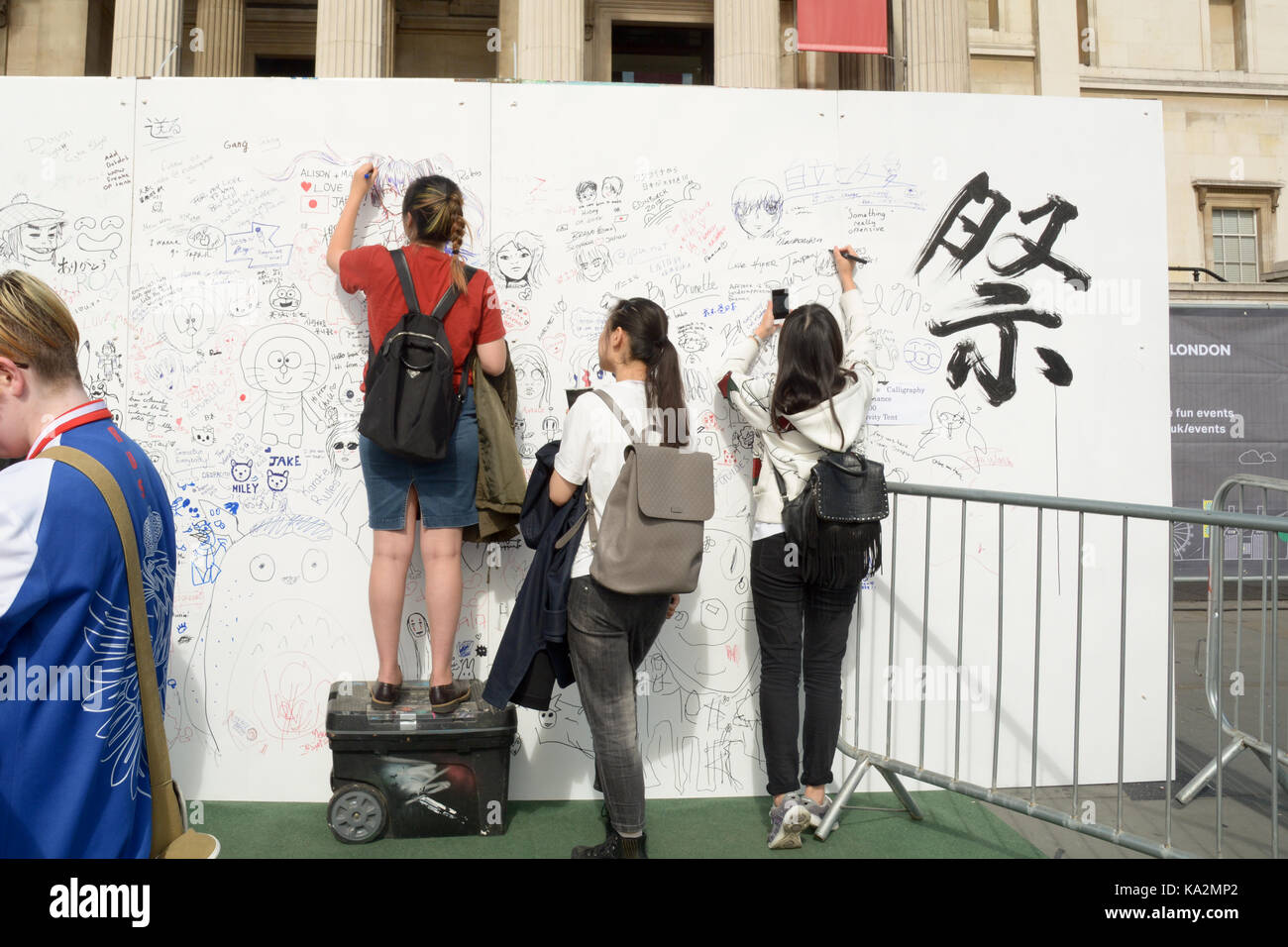 London, England. 24 September 2017: Children drawing and signing their names on the graffiti wall at the Japan Matsuri Festival in Trafalgar Square, London England. Martin Parker/Alamy Live News Stock Photo