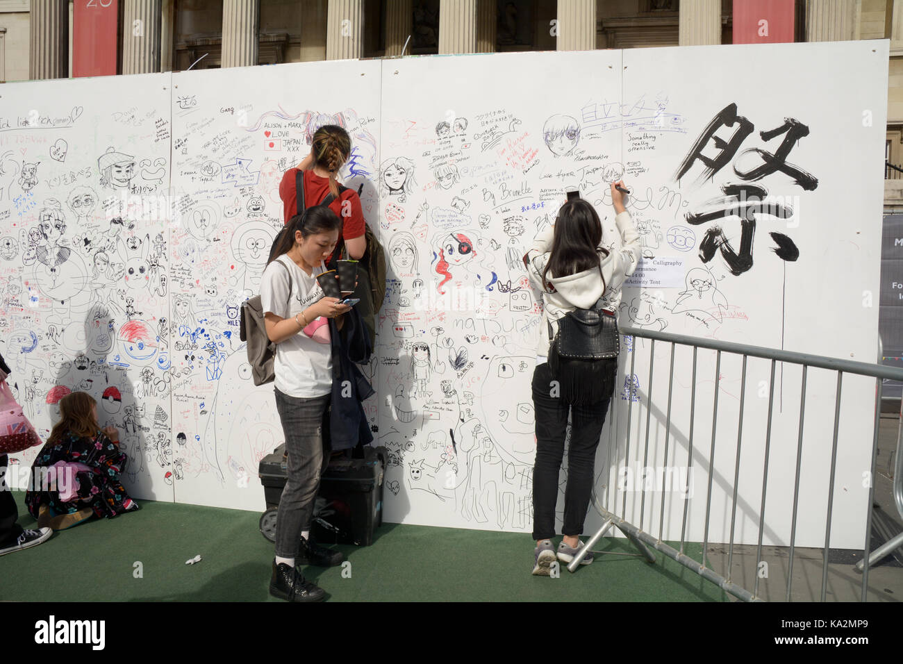 London, England. 24 September 2017: Children drawing and signing their names on the graffiti wall at the Japan Matsuri Festival in Trafalgar Square, London England. Martin Parker/Alamy Live News Stock Photo