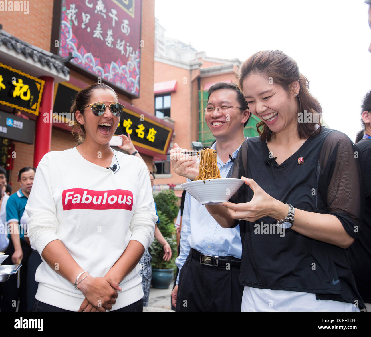 (170925) -- WUHAN, Sept. 25, 2017(Xinhua) -- Chinese two-time Grand Slam champion Li Na (R) and India's Sania Mirza taking part in 2017 WTA Wuhan Open try to taste traditional Wuhan food 'Hot Dry Noodle' in Wuhan, capital of central China's Hubei Province, on Sept. 25, 2017. (Xinhua/Xiao Yijiu)(wll) Stock Photo