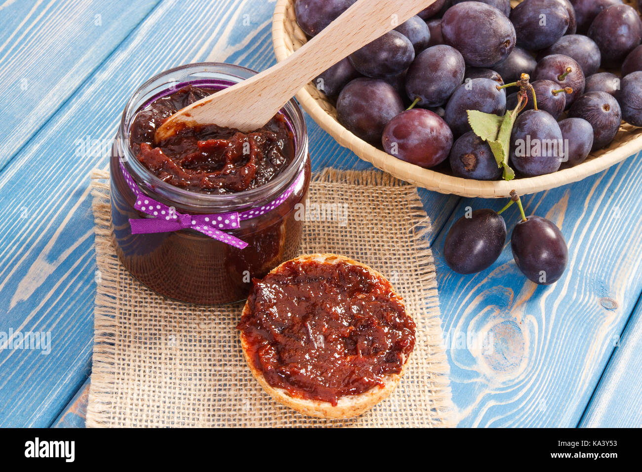 Wooden knife and plum marmalade or jam for preparing sandwiches, concept of healthy sweet snack or dessert Stock Photo