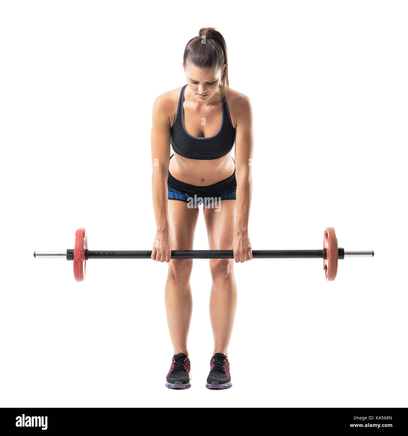 Front view of bent female athlete doing dead lift exercise with barbell looking down. Full body length portrait isolated on white studio background. Stock Photo