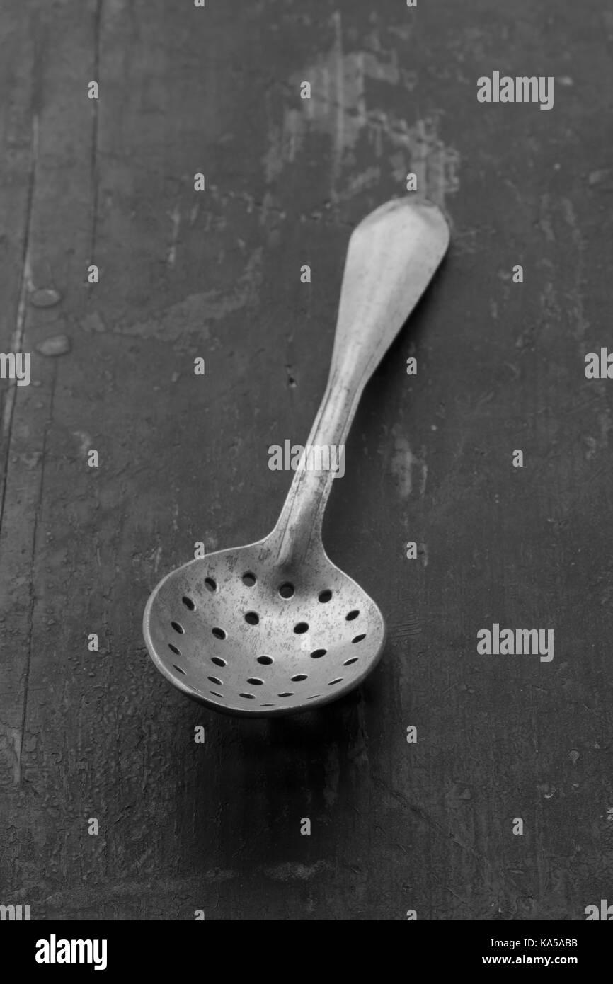 vintage aluminum spoon with holes on an old battered black table