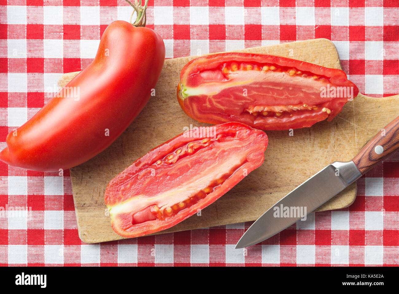 Halved San marzano tomatoes on cutting board. Top view Stock Photo - Alamy