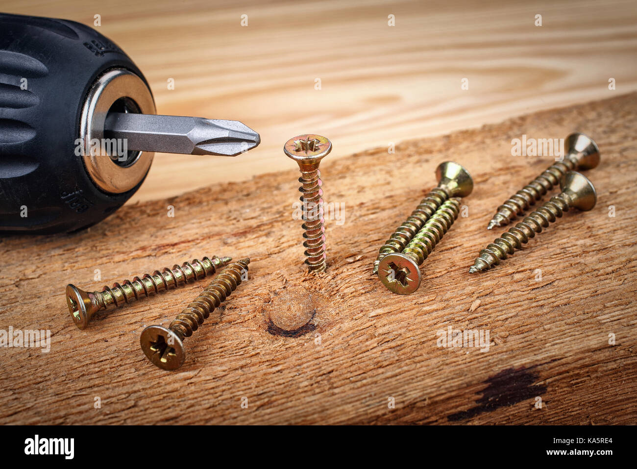 cordless drill and large screws on a wood background Stock Photo