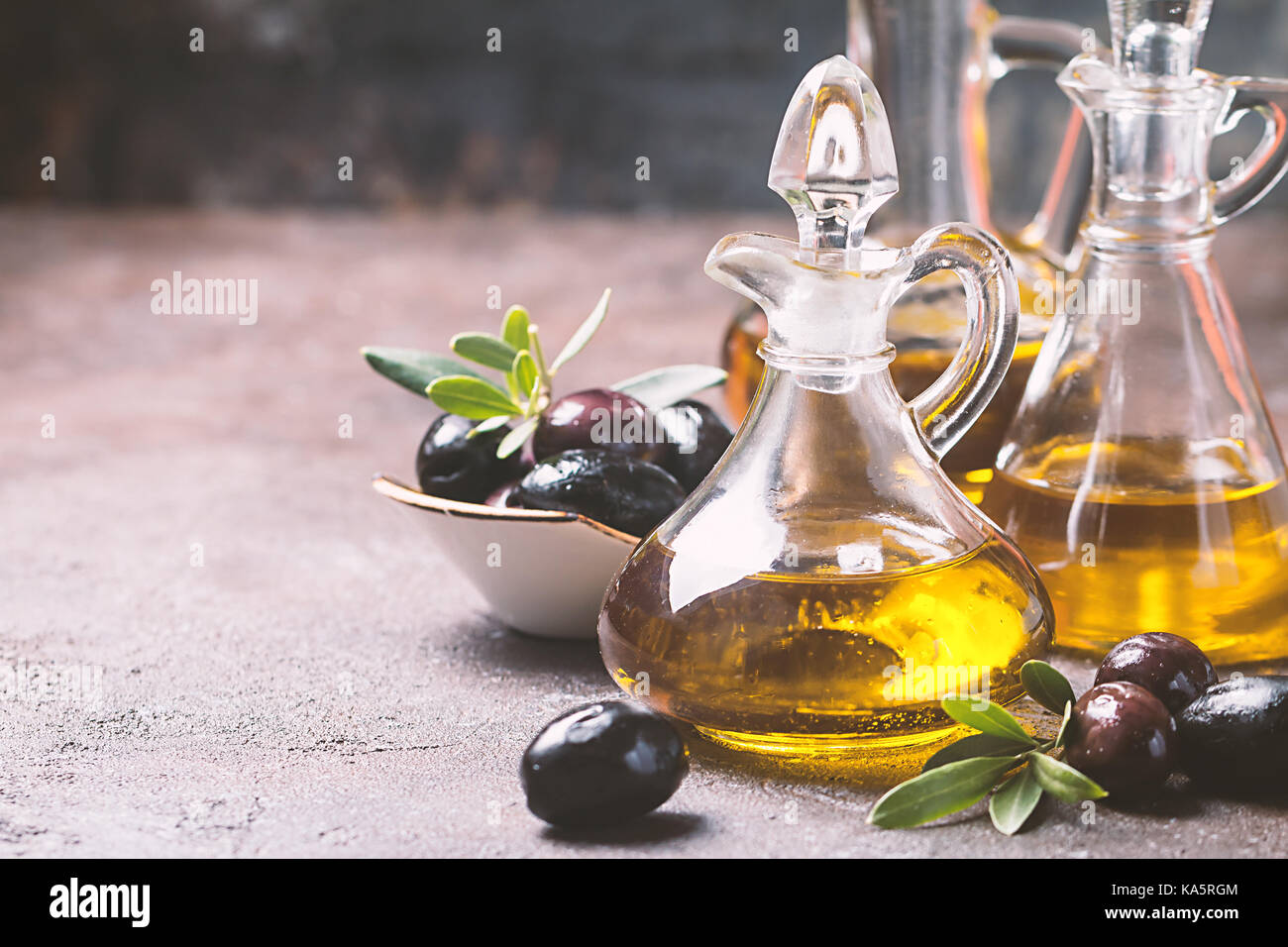 Olive oil in a glass bottle and olive branch on brown stone table Stock ...