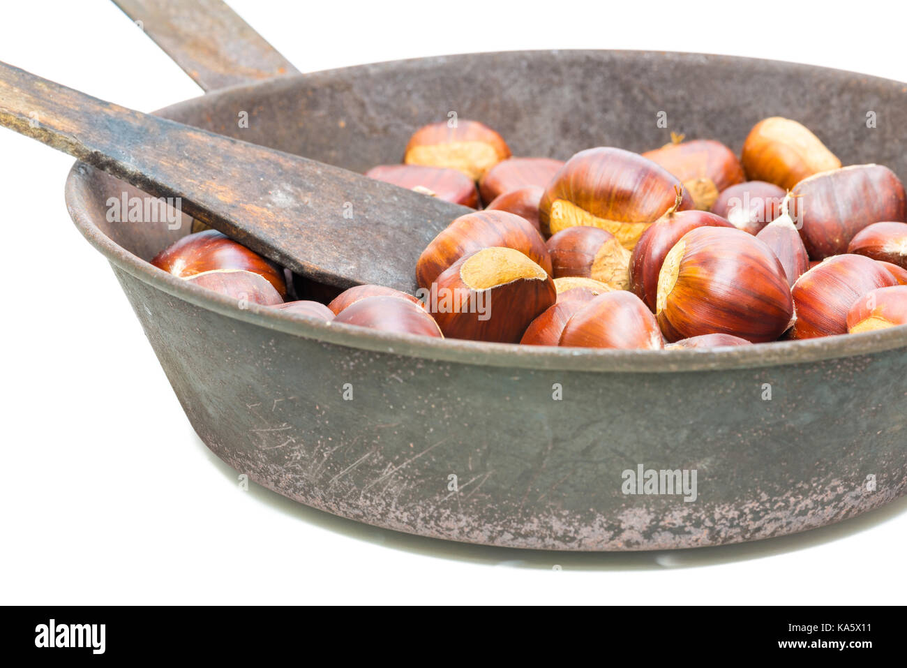 Chestnuts. Characteristic autumn fruit on white background. Fresh chestnuts in a old frying pan with holes on the bottom Stock Photo