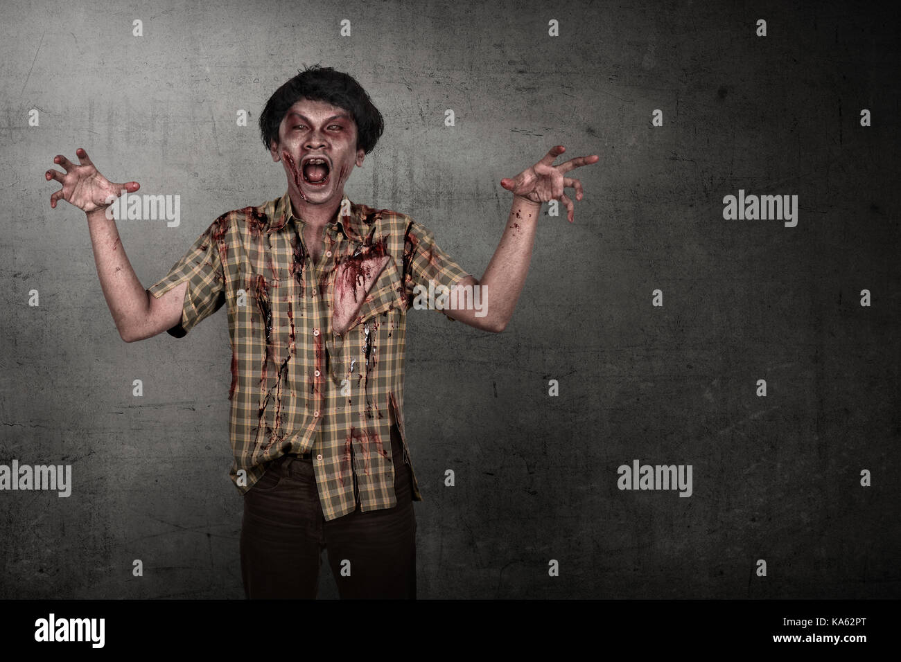 Aggressive asian zombie man with angry face over dirty wall background