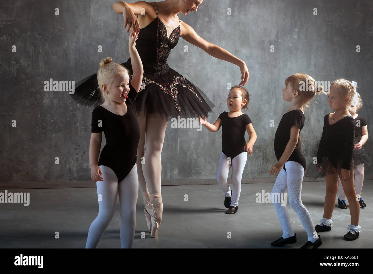 A beautiful blonde woman in a black dance tutu white pantyhose and pointe shoes is dancing and teaches young girls to dance ballet in a dark studio Stock Photo Alamy