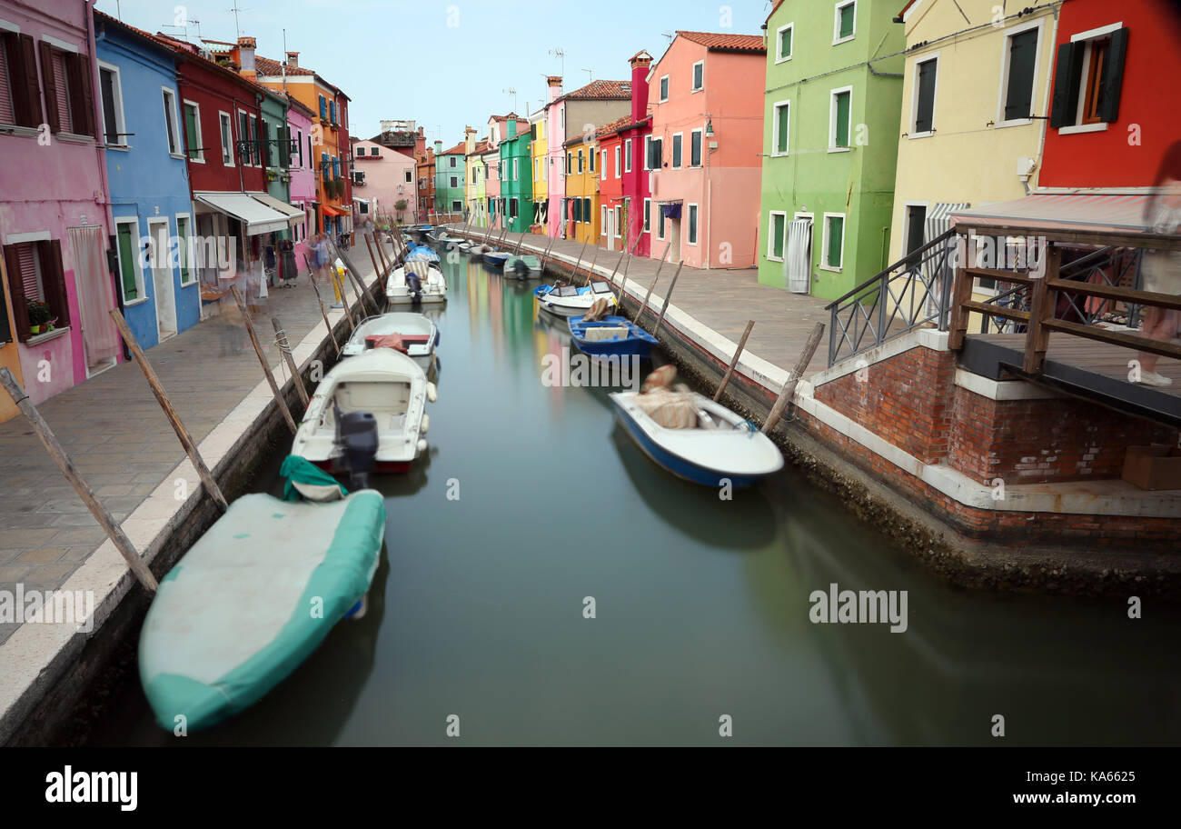 colored houses on the island of Burano in Venice in Italy with the boats slightly moved due to the long exposure of photography Stock Photo