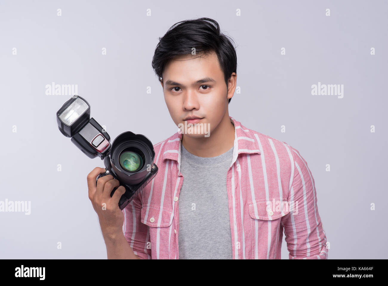 Young asian photographer holding digital camera, while working in ...