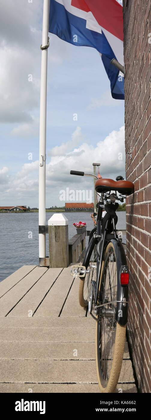 waving flag of the Netherlands with red white and blue and an old bike