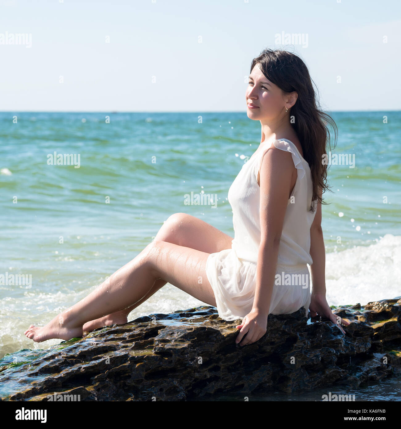 Happy young woman sitting on the beach Stock Photo - Alamy