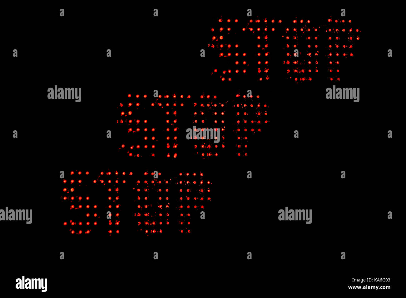 Photograph with illuminated Word Stop repeated three times on a black background. Stock Photo