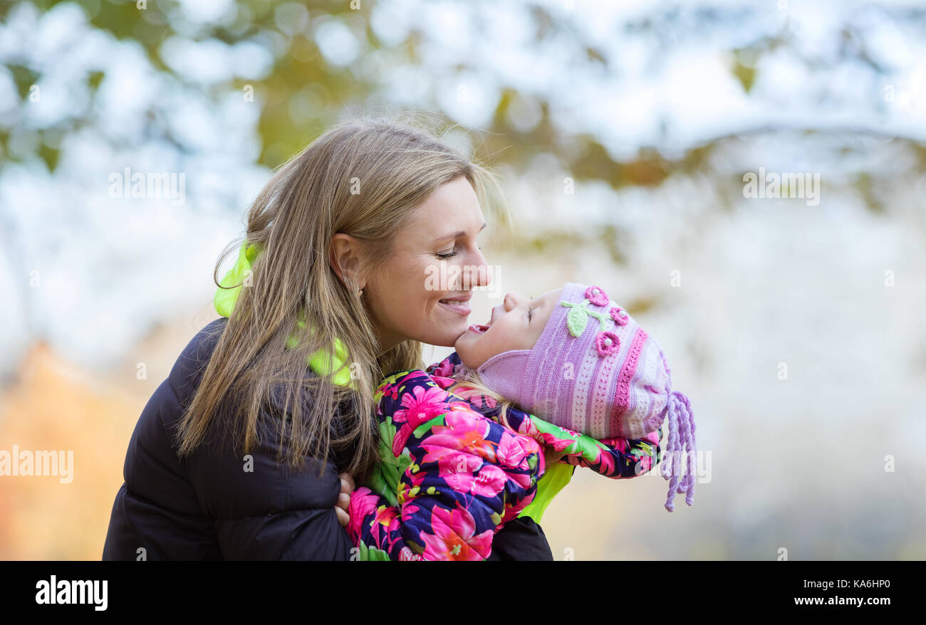 Young mother and daughter having fun in autumn park Stock Photo - Alamy