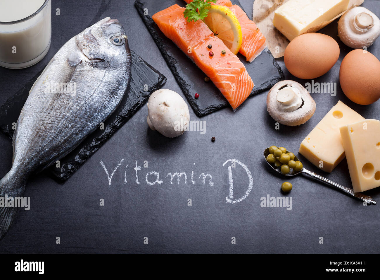 Black slate table with product rich in vitamin D and omega 3. Written word vitamin D by white chalk. Stock Photo