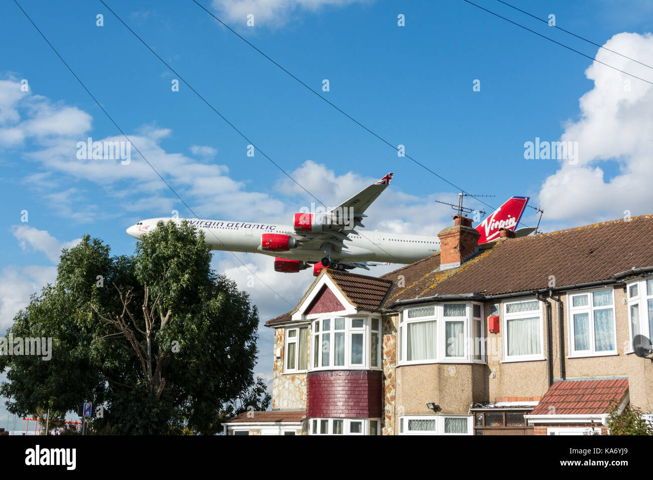 A Virgin Atlantic jet plane coming in to land as it flies over houses on Myrtle Avenue, in Hounslow, before landing at Heathrow Airport, Terminal 4. Stock Photo